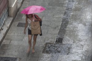 En la imagen, una mujer camina bajo la lluvia. EFE/Manuel Bruque/Archivo